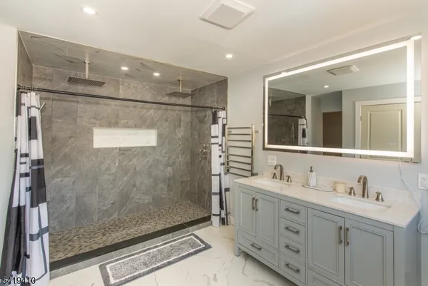 a bathroom with a double vanity sink mirror and shower