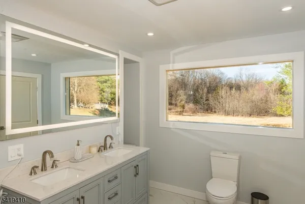 a bathroom with a sink vanity granite toilet and a window