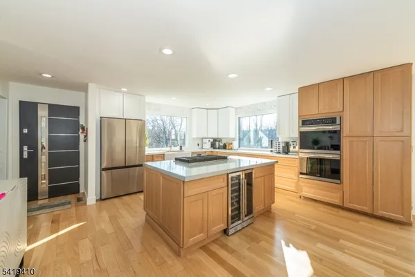 a kitchen with stainless steel appliances granite countertop a stove top oven a refrigerator a sink and dishwasher a oven with white cabinets