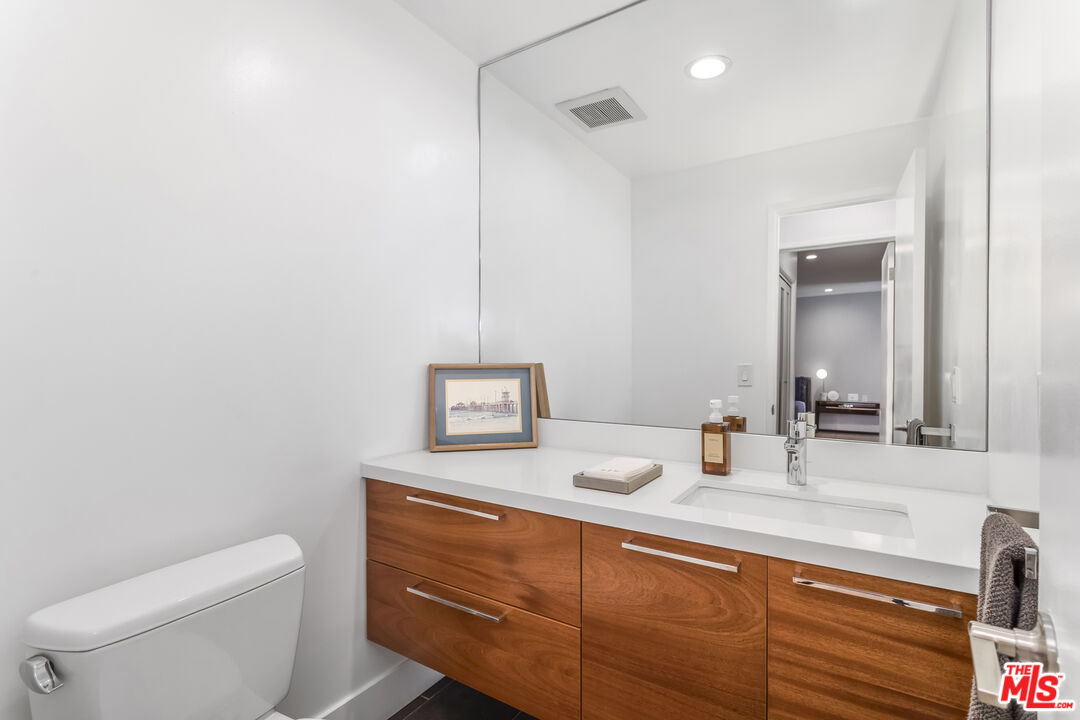 1221 North Kings Road, Unit 208 West Hollywood, CA 90069 - Photo 19 of 25 a bathroom with a toilet sink and mirror