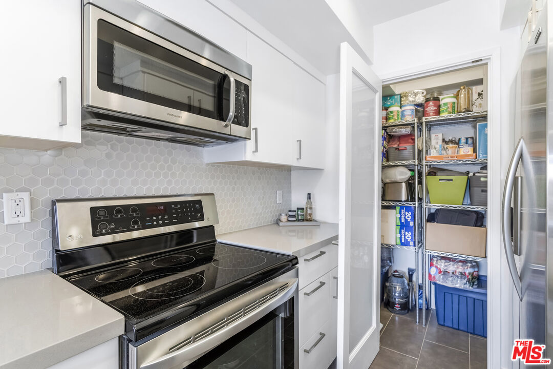 1221 North Kings Road, Unit 208 West Hollywood, CA 90069 - Photo 9 of 25 a kitchen with stainless steel appliances a stove a microwave and cabinets