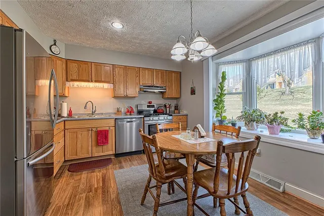 a kitchen with a refrigerator a stove a sink and white cabinets with wooden floor