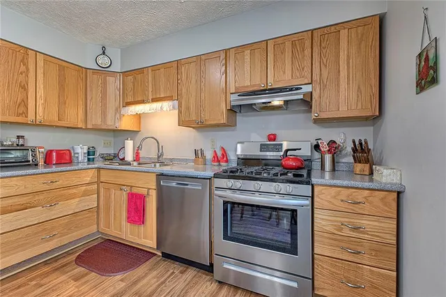 a kitchen with granite countertop wooden cabinets and stainless steel appliances