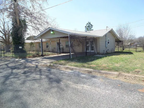 a wooden house with a yard and large tree