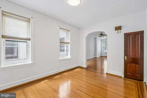 a view of empty room with wooden floor and fan