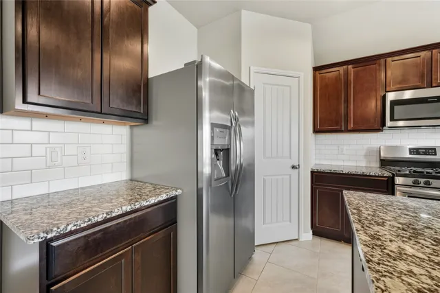 a kitchen with stainless steel appliances granite countertop a refrigerator and a stove top oven