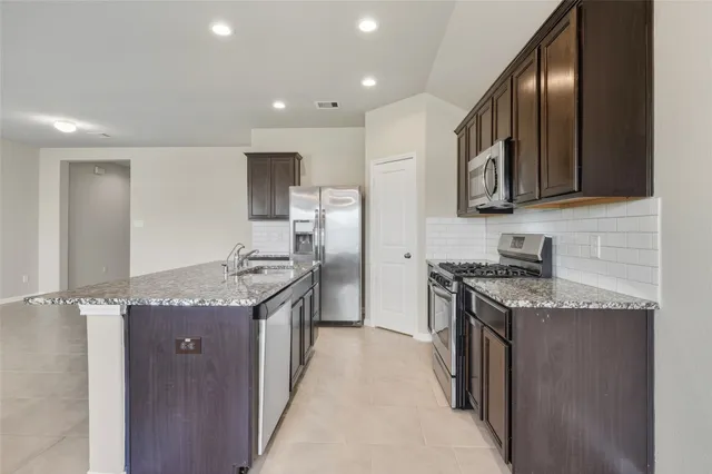a kitchen with stainless steel appliances granite countertop a stove a sink and a refrigerator