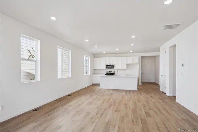 a large white kitchen with kitchen island a stove a sink and a large window