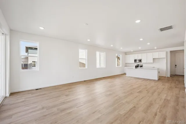 a view of a kitchen with a sink dishwasher and a refrigerator with wooden floor