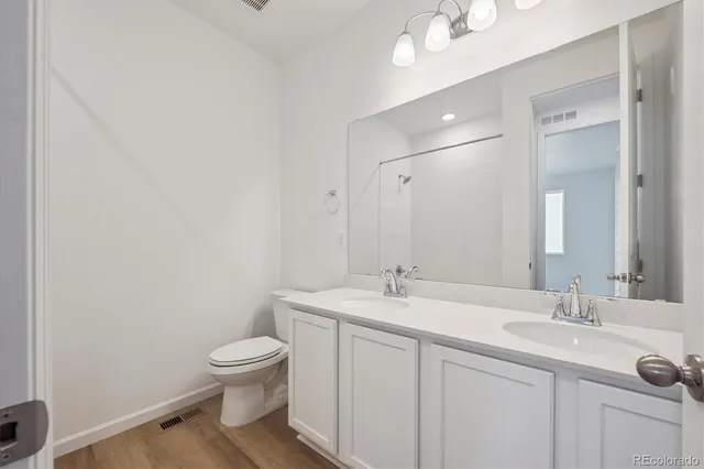 a bathroom with a toilet a sink a mirror and vanity