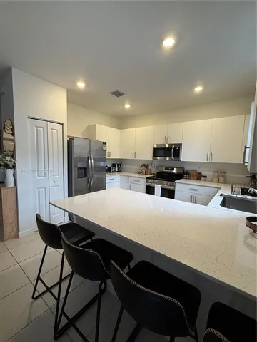 a kitchen with refrigerator and chairs