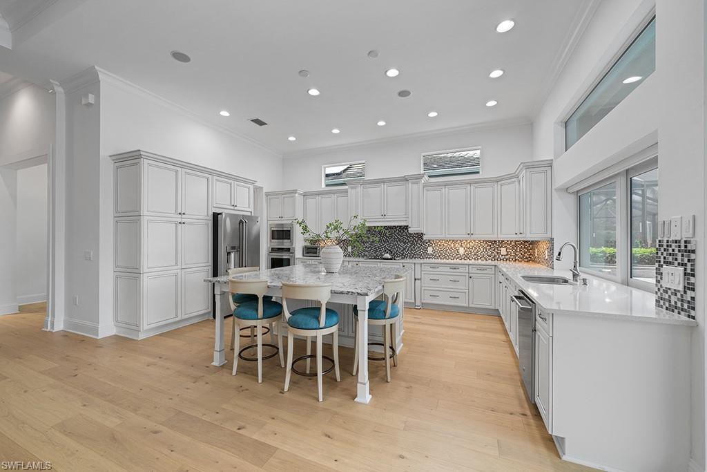 5154 Andros Drive Naples, FL 34113 - Photo 17 of 46 a kitchen with a dining table chairs wooden floor appliances and cabinets