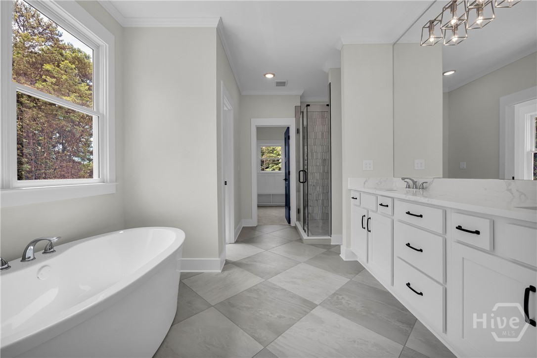 2476 St Martin Way Monroe, GA 30656 - Photo 40 of 75 Light-filled bathroom featuring a freestanding soaking tub, dual vanity with white cabinetry, a glass-enclosed shower, and checkered tile flooring
