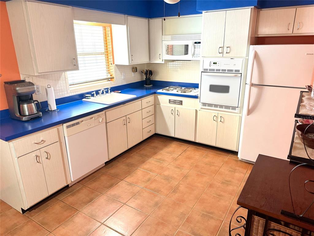 1035 Robmar Road Dunedin, FL 34698 - Photo 7 of 40 a kitchen with cabinets and white appliances