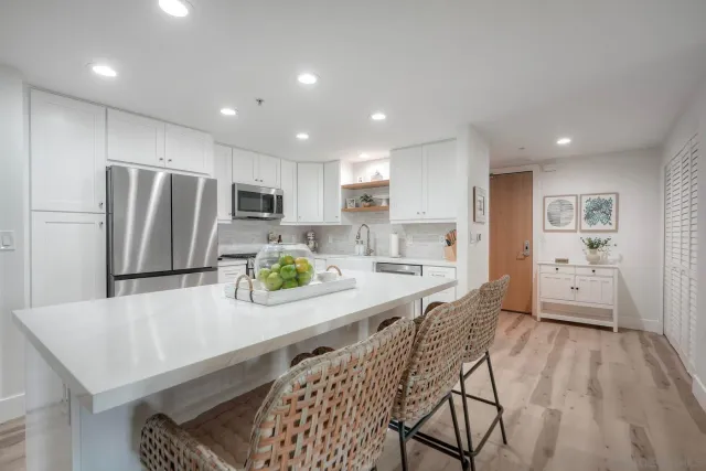 a kitchen with stainless steel appliances a refrigerator a sink a stove a dining table and chairs