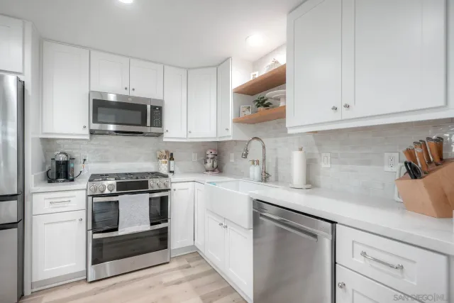 a kitchen with white cabinets and stainless steel appliances