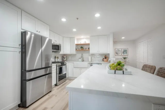 a kitchen with stainless steel appliances a refrigerator sink and white cabinets