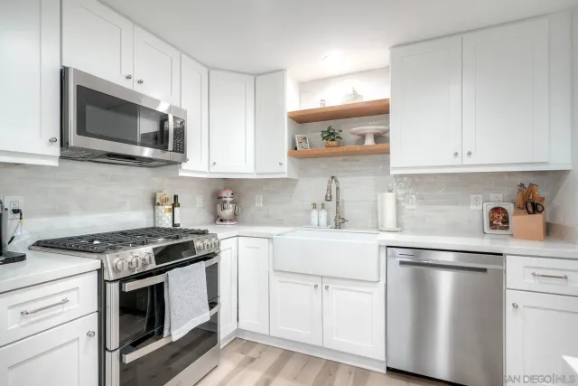a kitchen with stainless steel appliances granite countertop white cabinets a microwave a sink and a counter space