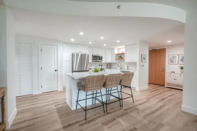 a kitchen with stainless steel appliances kitchen island granite countertop a dining table chairs refrigerator and sink