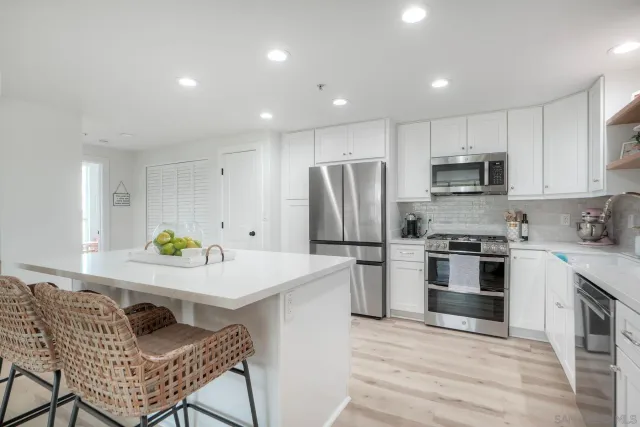 a kitchen with stainless steel appliances kitchen island granite countertop a refrigerator stove top oven and sink