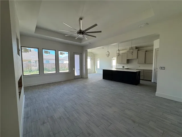 a view of a livingroom with a fireplace a ceiling fan and wooden floor