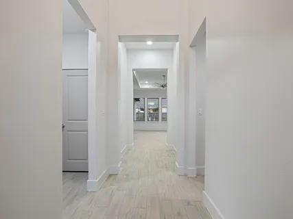 a view of a hallway with wooden floor and a bathroom