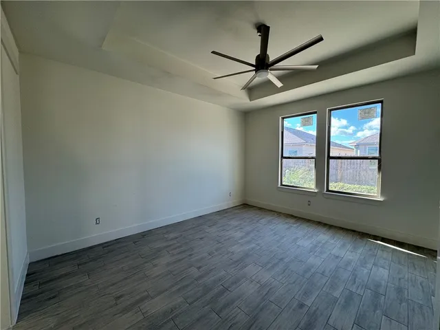 an empty room with wooden floor fan and windows