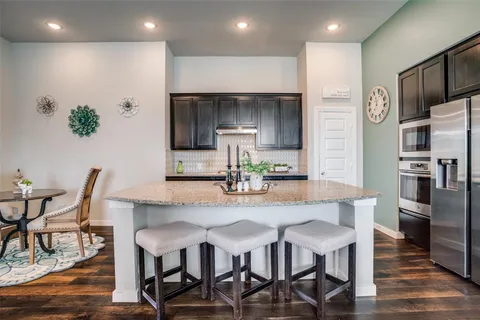 a kitchen with stainless steel appliances a dining table chairs refrigerator and microwave