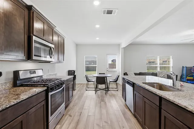 a kitchen with stainless steel appliances granite countertop a sink stove and cabinets