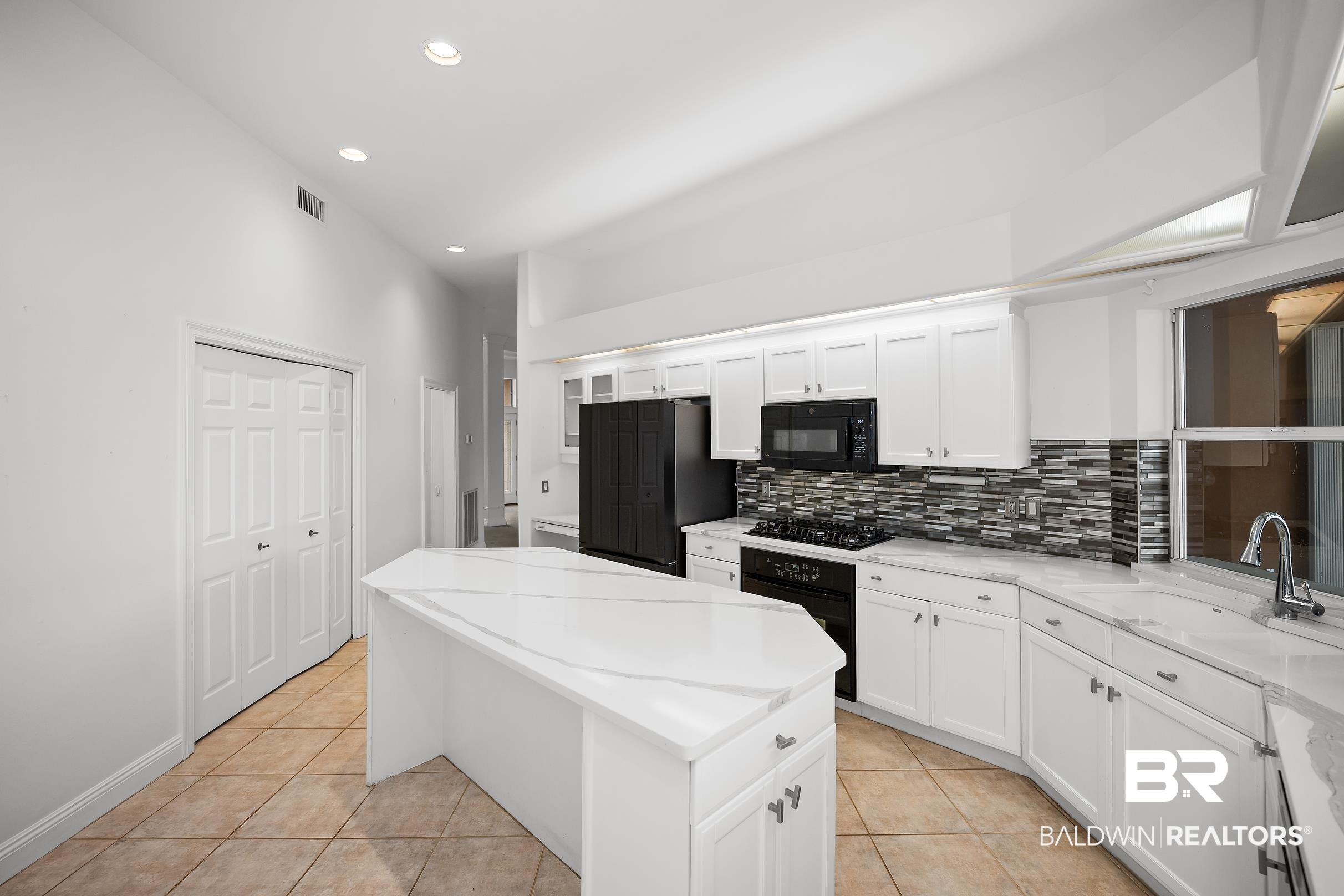 8591 Bay Harbor Road Elberta, AL 36530 - Photo 19 of 56 Kitchen featuring black appliances, light tile patterned floors, white cabinets, a kitchen island, and recessed lighting
