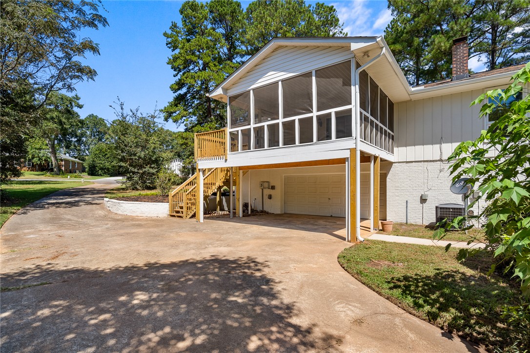 208 Williamsburg Road Anderson, SC 29621 - Photo 47 of 48 An elevated screened porch sits above the garage, bordered by a concrete driveway and mature trees.
