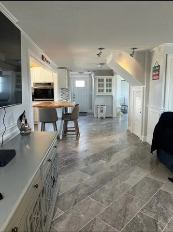 a living room with stainless steel appliances furniture and a flat screen tv