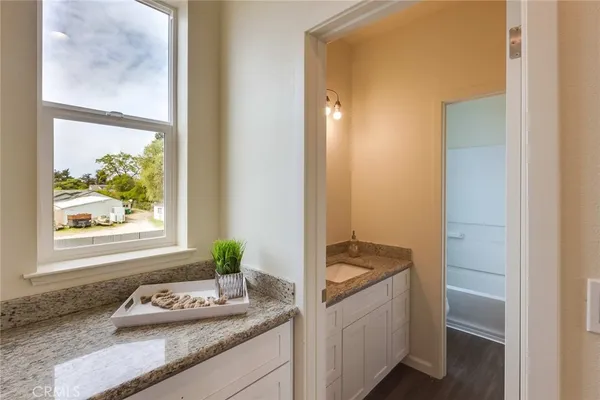 a bathroom with a granite countertop sink and a window