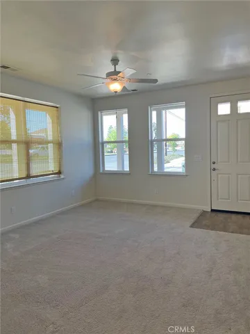 an empty room with windows and chandelier fan