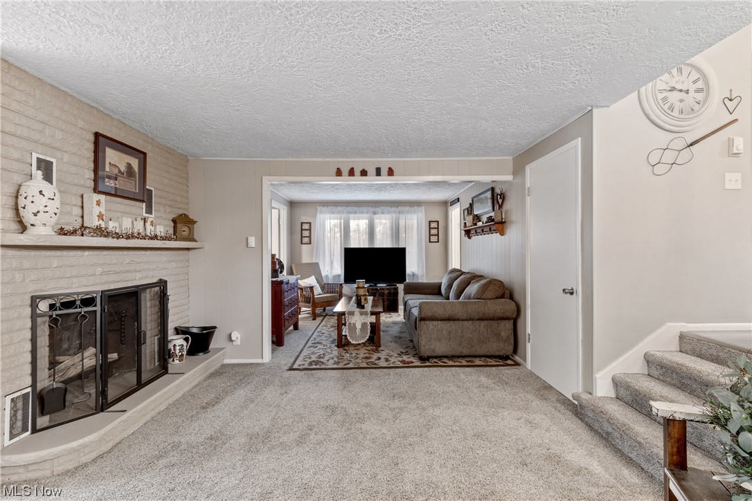 5369 Ridge Avenue Southeast Canton, OH 44707 - Photo 12 of 33 Carpeted living room with a brick fireplace and a textured ceiling
