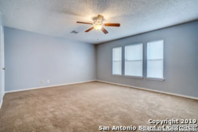 an empty room with windows and chandelier fan