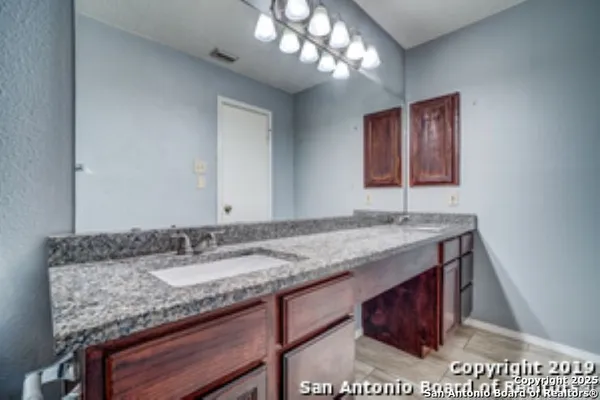 a bathroom with a granite countertop sink and a mirror