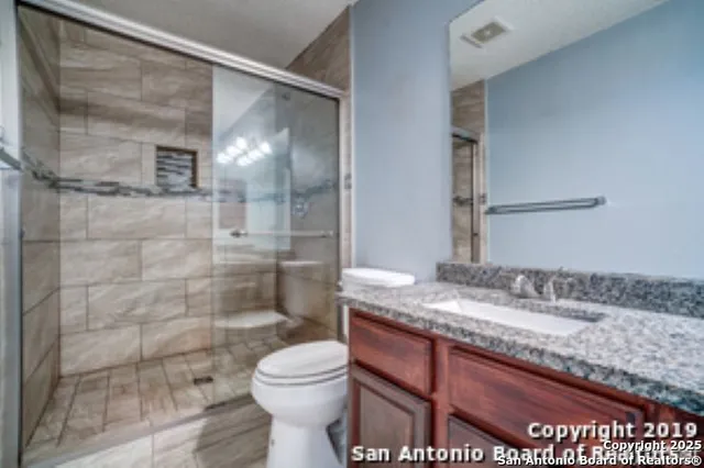 a bathroom with a granite countertop sink toilet and shower