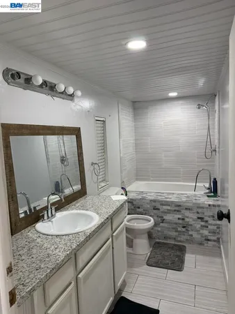 a bathroom with a granite countertop sink a toilet and a mirror