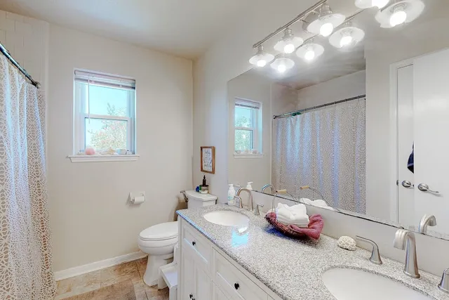 a bathroom with a granite countertop toilet a sink and a mirror