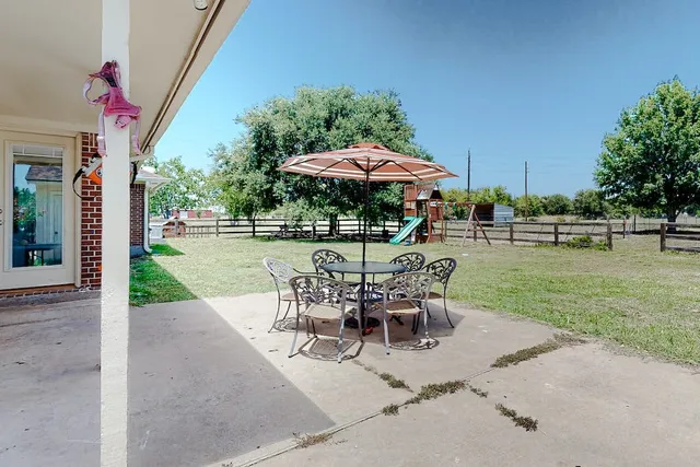 a view of a patio with a table and chairs under an umbrella