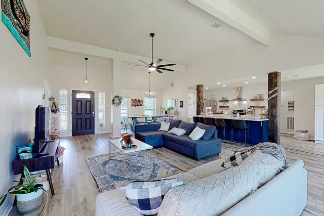 a living room with furniture kitchen view and a chandelier