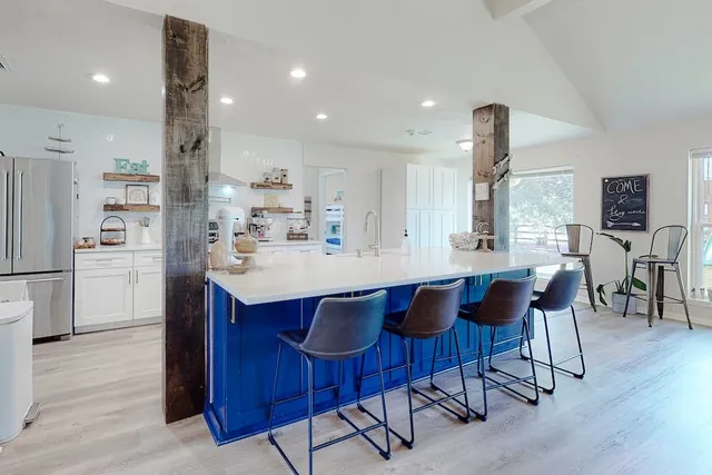 a kitchen with stainless steel appliances a dining table chairs and wooden floor