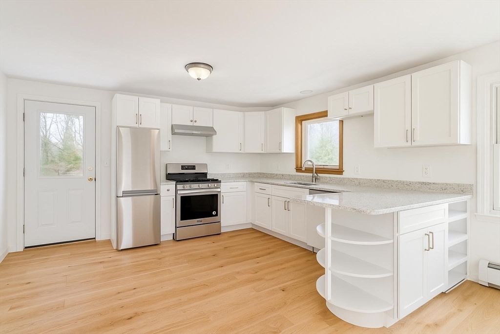 73 Spur Road Dover, NH 03820 - Photo 3 of 26 a kitchen with granite countertop white cabinets and white appliances