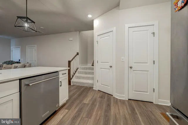 a view of a kitchen with a sink and dishwasher with wooden floor