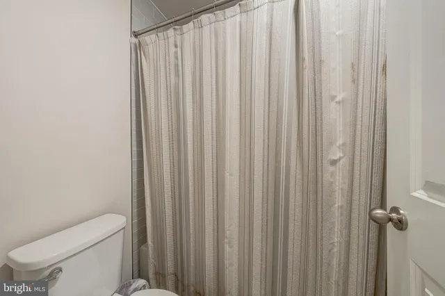 a bathroom with a toilet a sink and curtain
