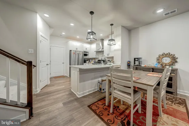 a kitchen with stainless steel appliances kitchen island granite countertop a table chairs and a refrigerator