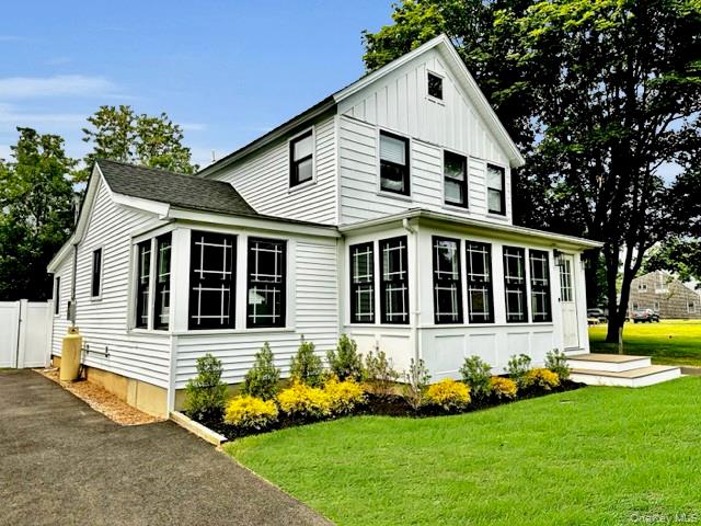 275 Sound Road Greenport, NY 11944 - Photo 2 of 33 View of property exterior with a yard, asphalt driveway, board and batten siding, and a gate