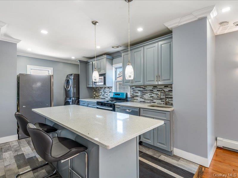 176-27 Sunbury Road Queens, NY 11434 - Photo 14 of 31 Kitchen featuring crown molding, light wood-type flooring, a kitchen bar, gray cabinets, and a kitchen island