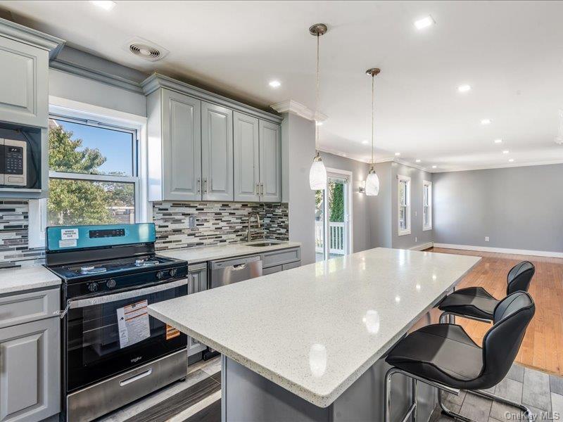 176-27 Sunbury Road Queens, NY 11434 - Photo 30 of 31 Kitchen with gray cabinetry, appliances with stainless steel finishes, open floor plan, pendant lighting, and tasteful backsplash